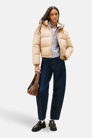 Korte beige jas van Tommy Jeans, gedragen met een gestreept overhemd, een blauwe spijkerbroek en een tas met luipaardprint.