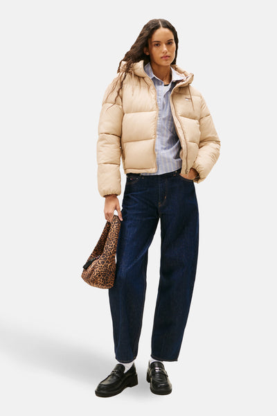 Korte beige jas van Tommy Jeans, gedragen met een gestreept overhemd, een blauwe spijkerbroek en een tas met luipaardprint.