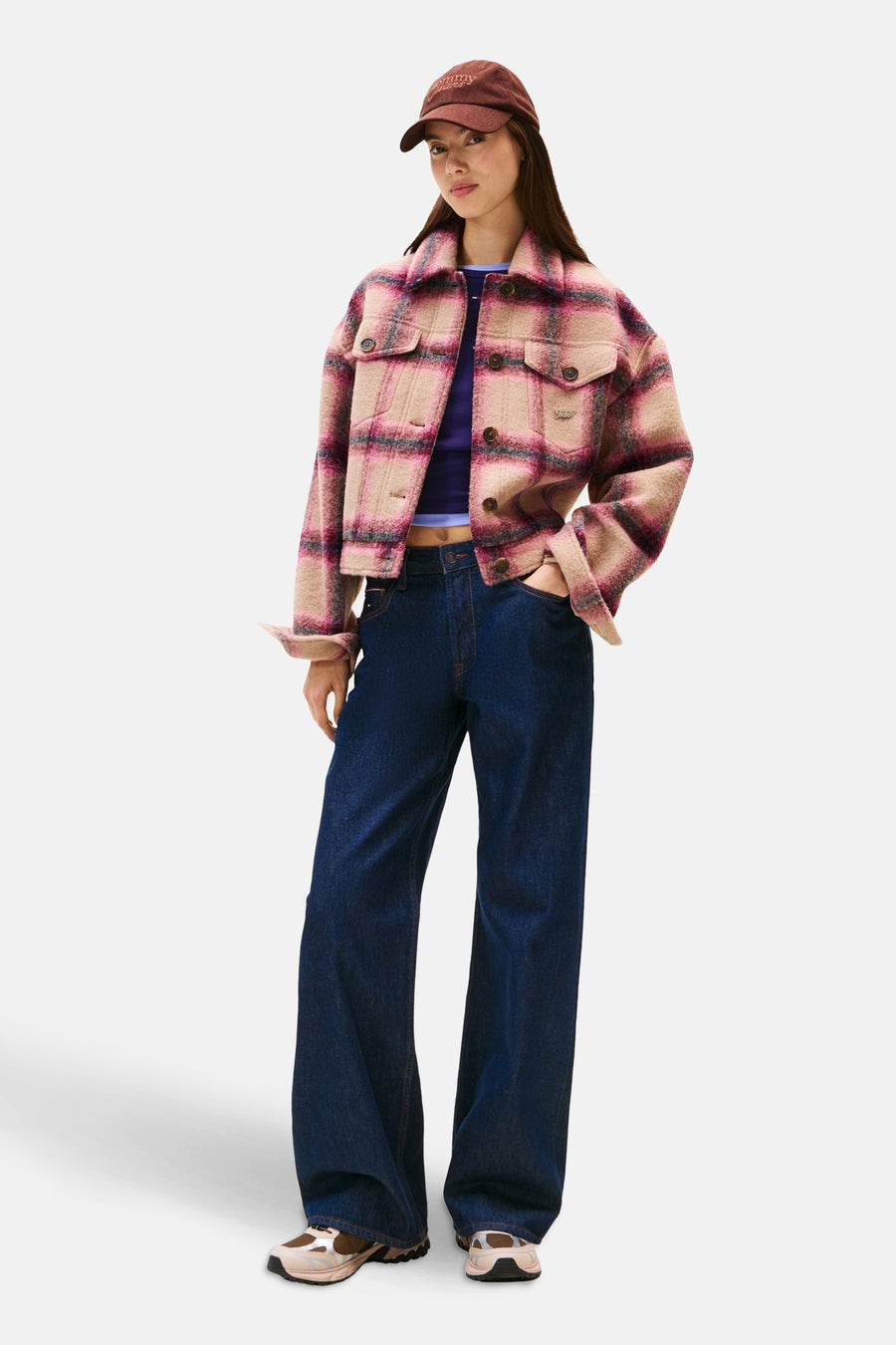 Veste courte multicolore par Tommy Jeans, à carreaux, portée avec un jean bleu large et des baskets.
