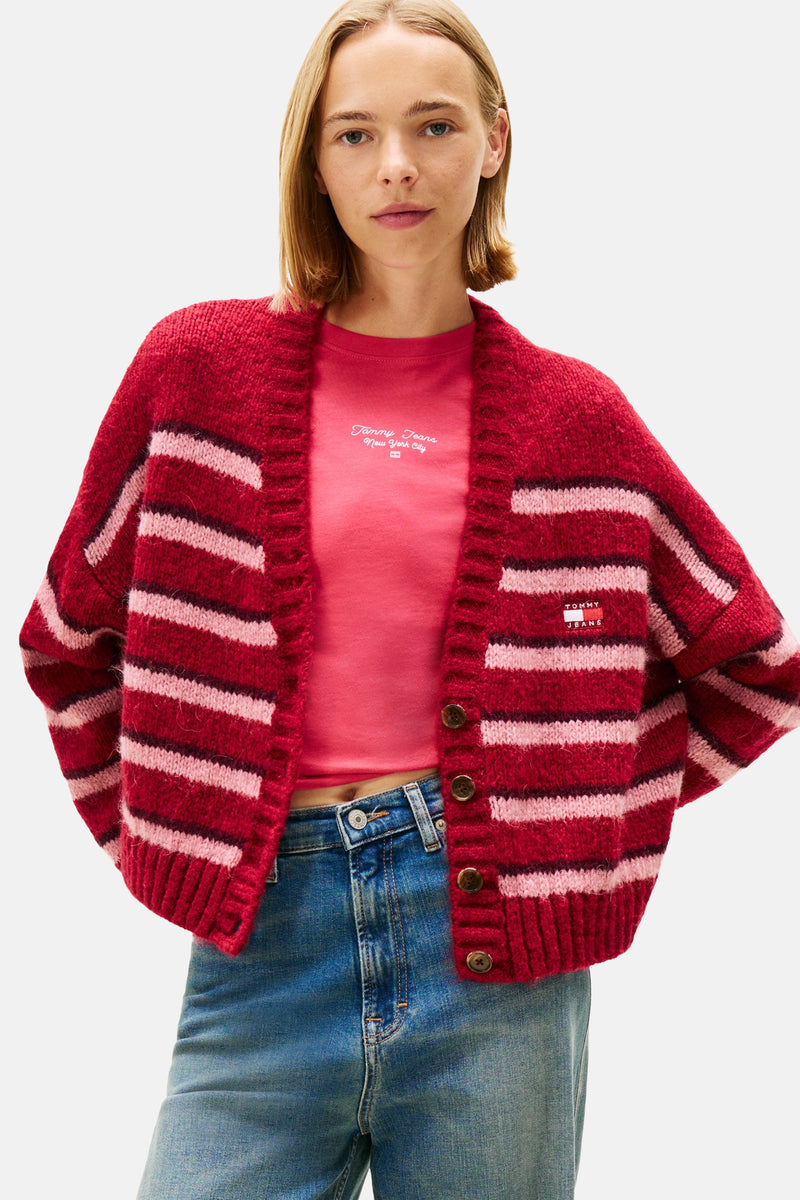 Gilet rouge à rayures roses de Tommy Jeans, porté sur un t-shirt rose et un jean bleu.