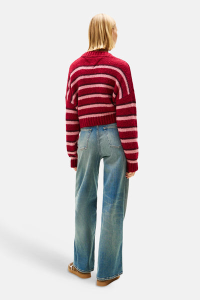 Gilet rayé rouge, rose et bordeaux de TOMMY JEANS, porté avec un jean taille haute.
