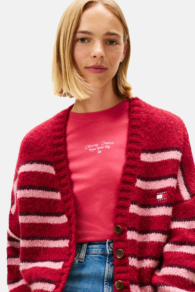 Gilet rouge rayé en tricot, de Tommy Jeans, porté sur un t-shirt rouge et un jean bleu.