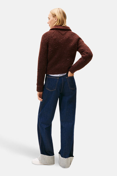 Bruine trui van Tommy Jeans, met gespikkelde details, gedragen met een donkerblauwe jeans met grijze omslag.