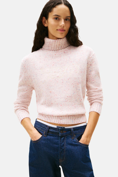 Roze coltrui van Tommy Jeans, gedragen met een donkerblauwe low-rise jeans en een witte slip.