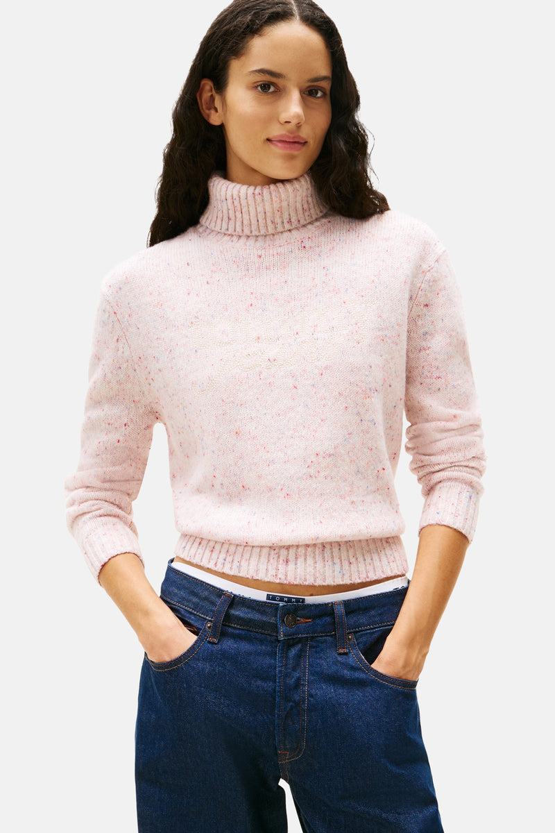 Roze coltrui van Tommy Jeans, gedragen met een donkerblauwe low-rise jeans en een witte slip.