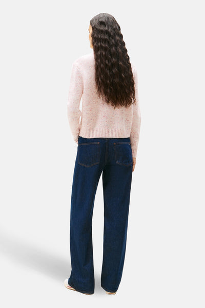Roze coltrui van TOMMY JEANS, gedragen met een donkerblauwe jeans en witte schoenen.