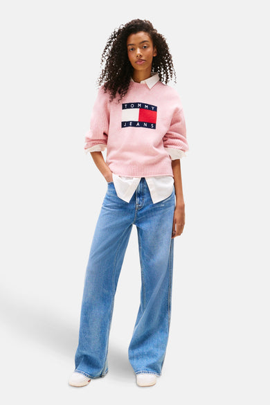 Roze gebreide trui met ronde hals van TOMMY JEANS gedragen met een witte blouse en een wijde jeans.