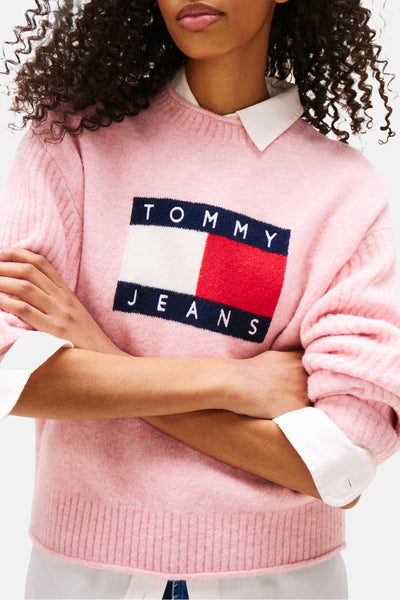Roze rondehals-trui van pluizig breiwerk van TOMMY JEANS, gedragen over een wit overhemd met rechthoekig logo.