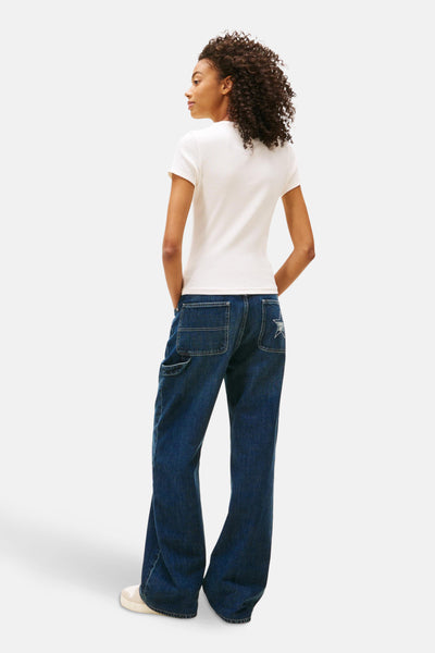 Wit T-shirt met korte mouwen van TOMMY JEANS, gedragen met een wijde donkerblauwe spijkerbroek.