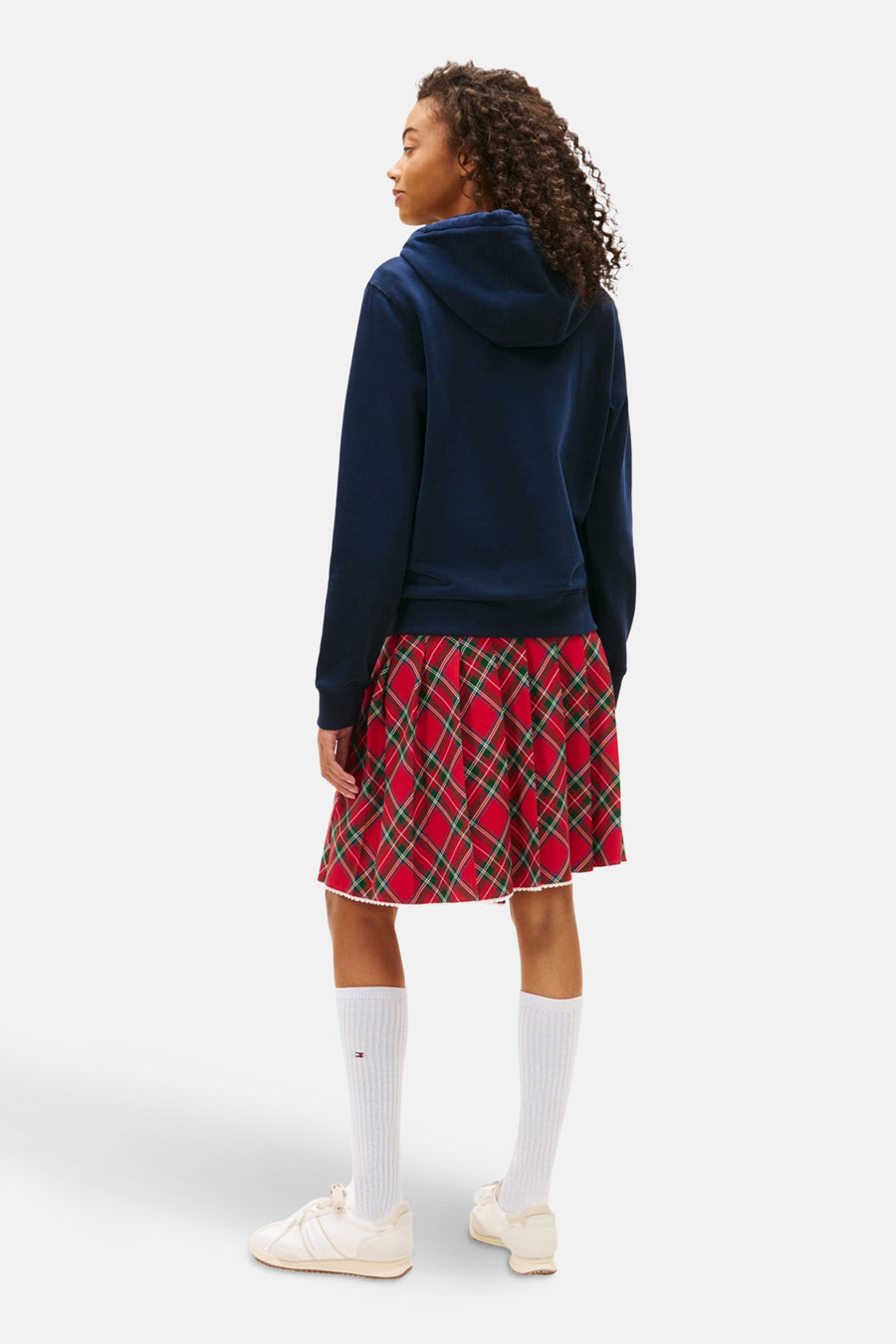 Blauwe hoodie van TOMMY JEANS, gedragen met een geruite plooirok en hoge sokken.