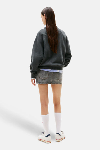 Grijze sweater van TOMMY JEANS, ronde hals, gedragen met een spijkerrok en witte sokken.