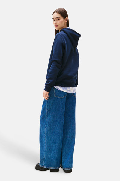 Blauwe hoodie van TOMMY JEANS, gedragen met een gestreept overhemd en een wijde jeans, achterzicht.