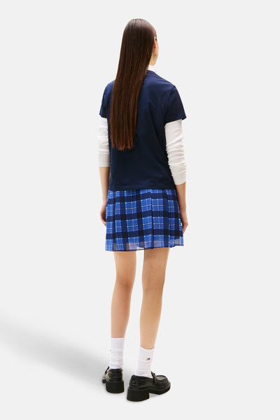 Blauw T-shirt met korte mouwen van TOMMY JEANS, gedragen met een T-shirt met lange mouwen en een geruite plooirok.
