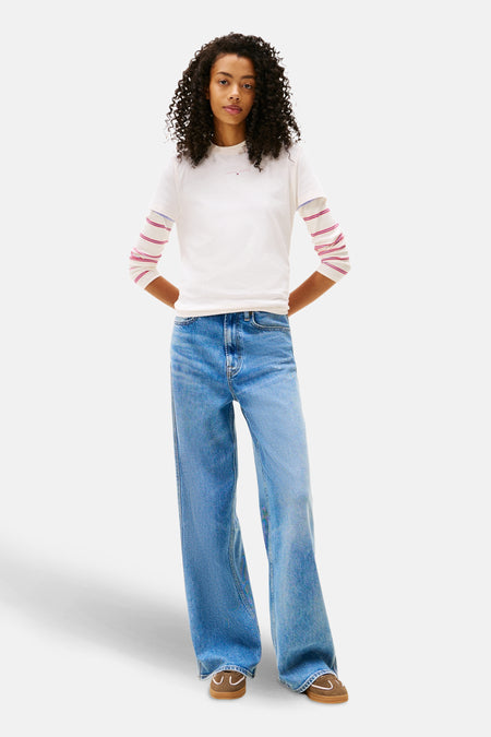 Wit T-shirt met korte mouwen van Tommy Jeans, gedragen met een gestreept T-shirt en een jeans met hoge taille.