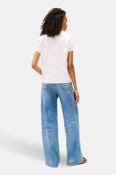 Wit T-shirt met korte mouwen van TOMMY JEANS, gedragen met een wijde blauwe jeans.