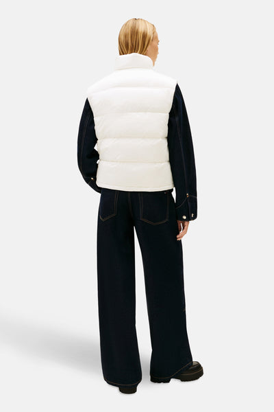 Veste sans manches blanche de TOMMY JEANS, portée avec une veste en jean et un pantalon foncé, vue de dos.
