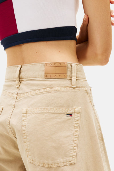 Pantalon beige de TOMMY JEANS avec une coupe droite et une étiquette de logo en cuir à l'arrière.