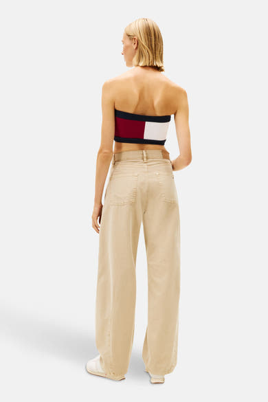 Beige broek van TOMMY JEANS, wijd, met achterzakken, gedragen met een gestreepte tube top in kleur.
