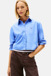 Blauwe blouse met lange mouwen van TOMMY JEANS, gedragen met een wijde bruine broek.