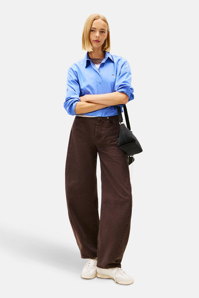 Blauw overhemd met lange mouwen van TOMMY JEANS, gedragen met een wijde bruine broek en een zwarte tas.