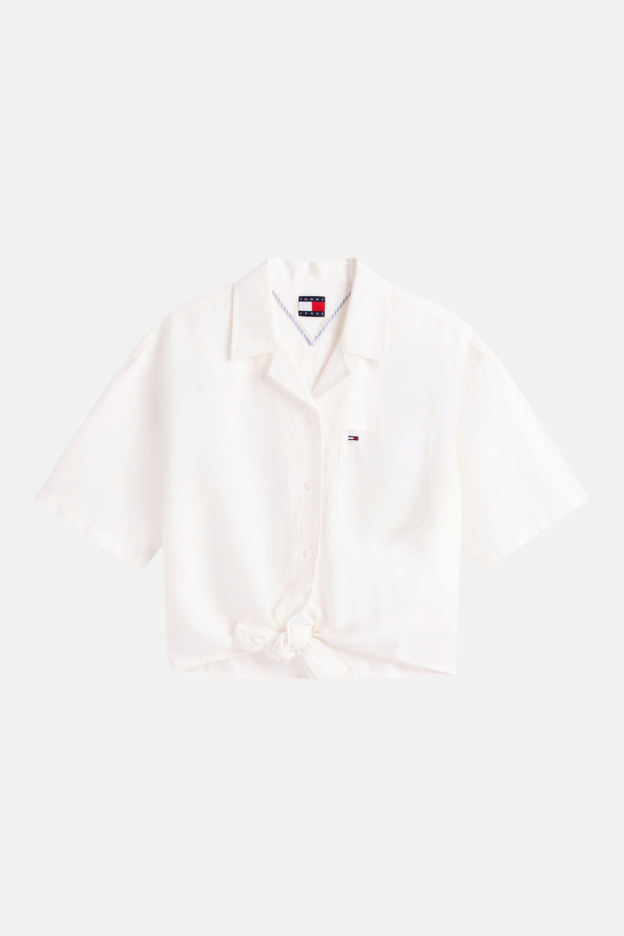 Chemisier blanc à manches courtes de TOMMY JEANS, noué sur le devant, avec poche poitrine et badge drapeau.