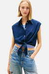 Blauw mouwloos overhemd van TOMMY JEANS, met strik in de taille, gedragen met een wijde jeans en plateauzolen.