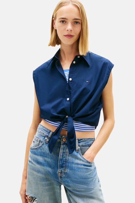Blauw mouwloos overhemd van TOMMY JEANS, met strik in de taille, gedragen met een wijde jeans en plateauzolen.
