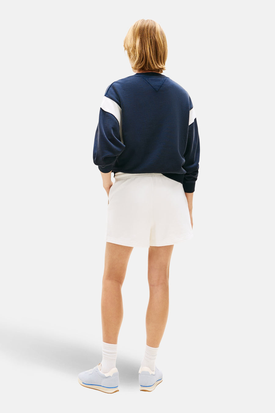 Kort wit T-shirt van TOMMY JEANS, gedragen met een marineblauw sweatshirt met lange mouwen.