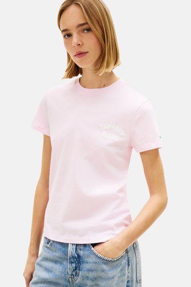 Roze T-shirt met korte mouwen van TOMMY JEANS, met een wit logo op de borst, gedragen met een wijde gescheurde spijkerbroek.