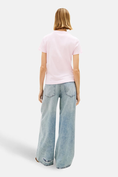 Roze T-shirt met korte mouwen van TOMMY JEANS, gedragen met een wijde, lichtgewassen spijkerbroek, achtergezicht.