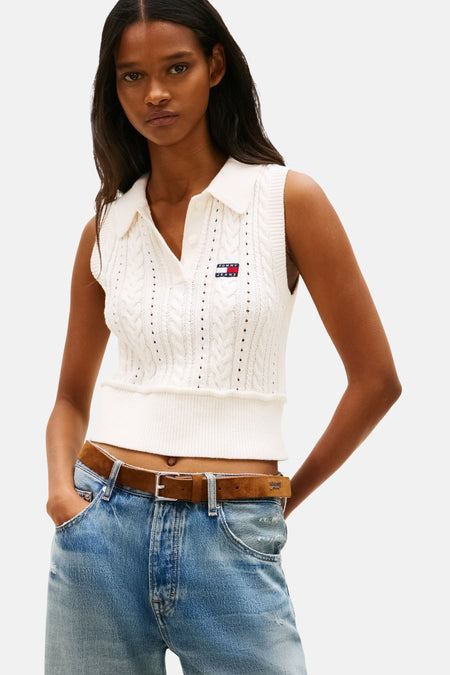 Débardeur tricoté blanc par TOMMY JEANS, avec motif torsadé et porté avec un jean taille basse et une ceinture marron.
