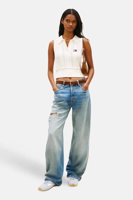 Débardeur blanc en maille, de Tommy Jeans, porté avec un jean ample taille basse et une ceinture marron.