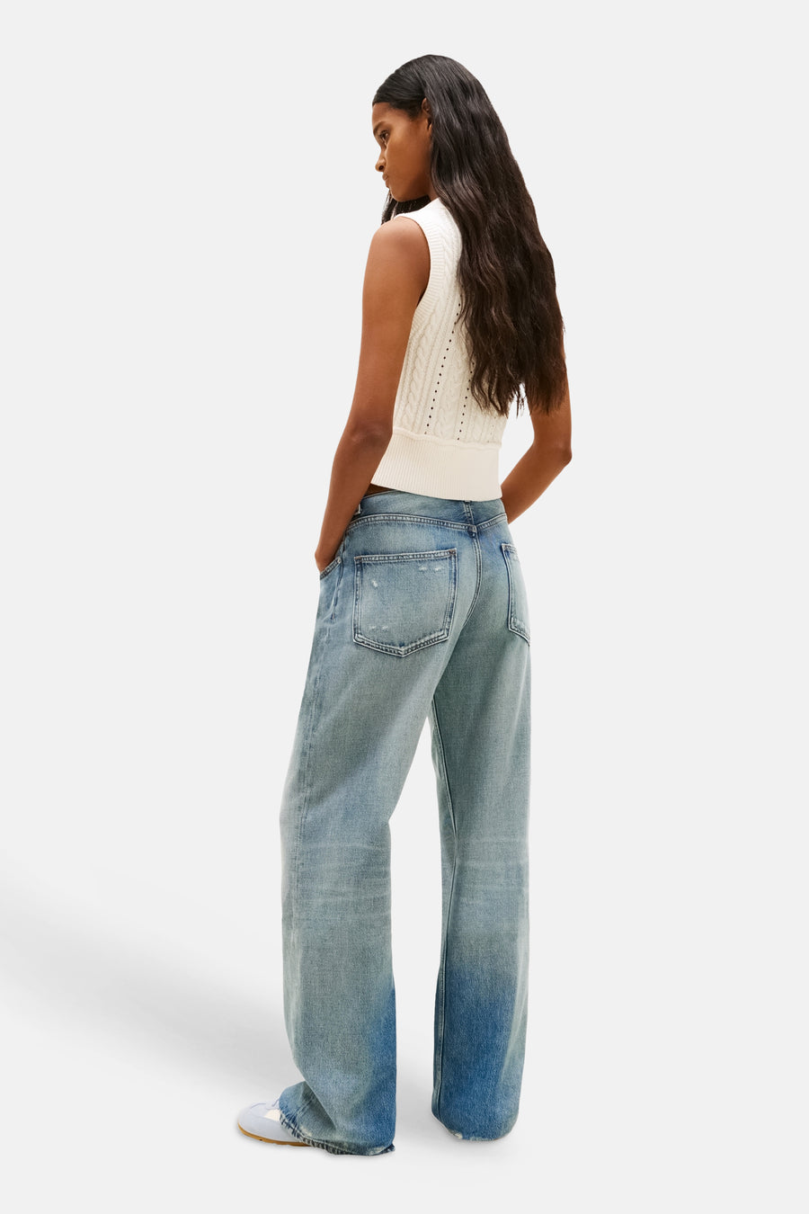 Débardeur blanc de TOMMY JEANS, en tricot torsadé, porté avec un jean bleu délavé à jambes larges.