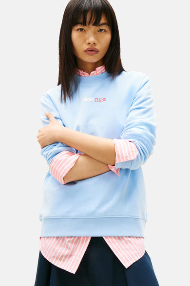 Sweat-shirt bleu par TOMMY JEANS avec superposition d'une chemise rayée rose et blanche.