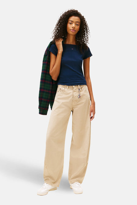 T-shirt bleu à manches courtes de Tommy Jeans, porté avec un pantalon beige ample et une veste à carreaux.
