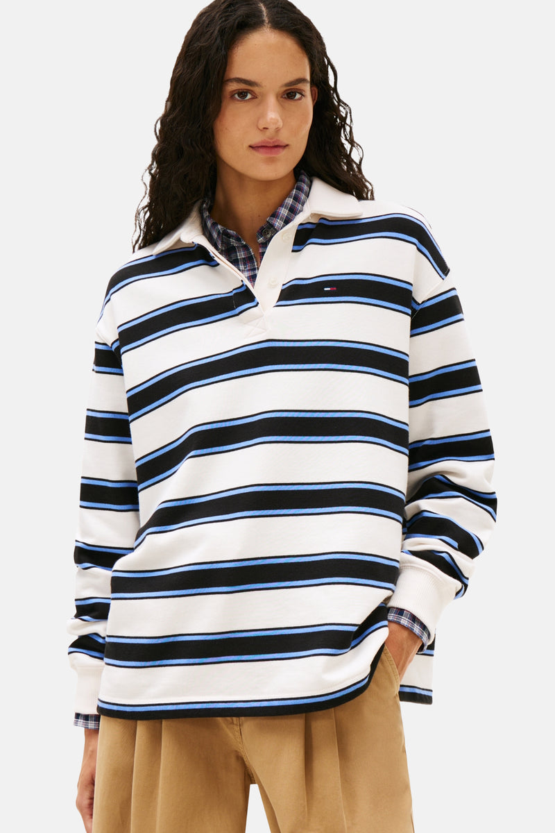 Polo à manches longues rayé multicolore de TOMMY JEANS, porté sur une chemise à carreaux et un pantalon beige