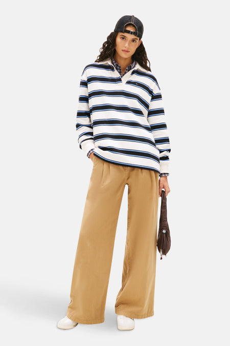 Polo à manches longues multicolore de TOMMY JEANS avec rayures horizontales, porté avec un pantalon beige et une casquette.