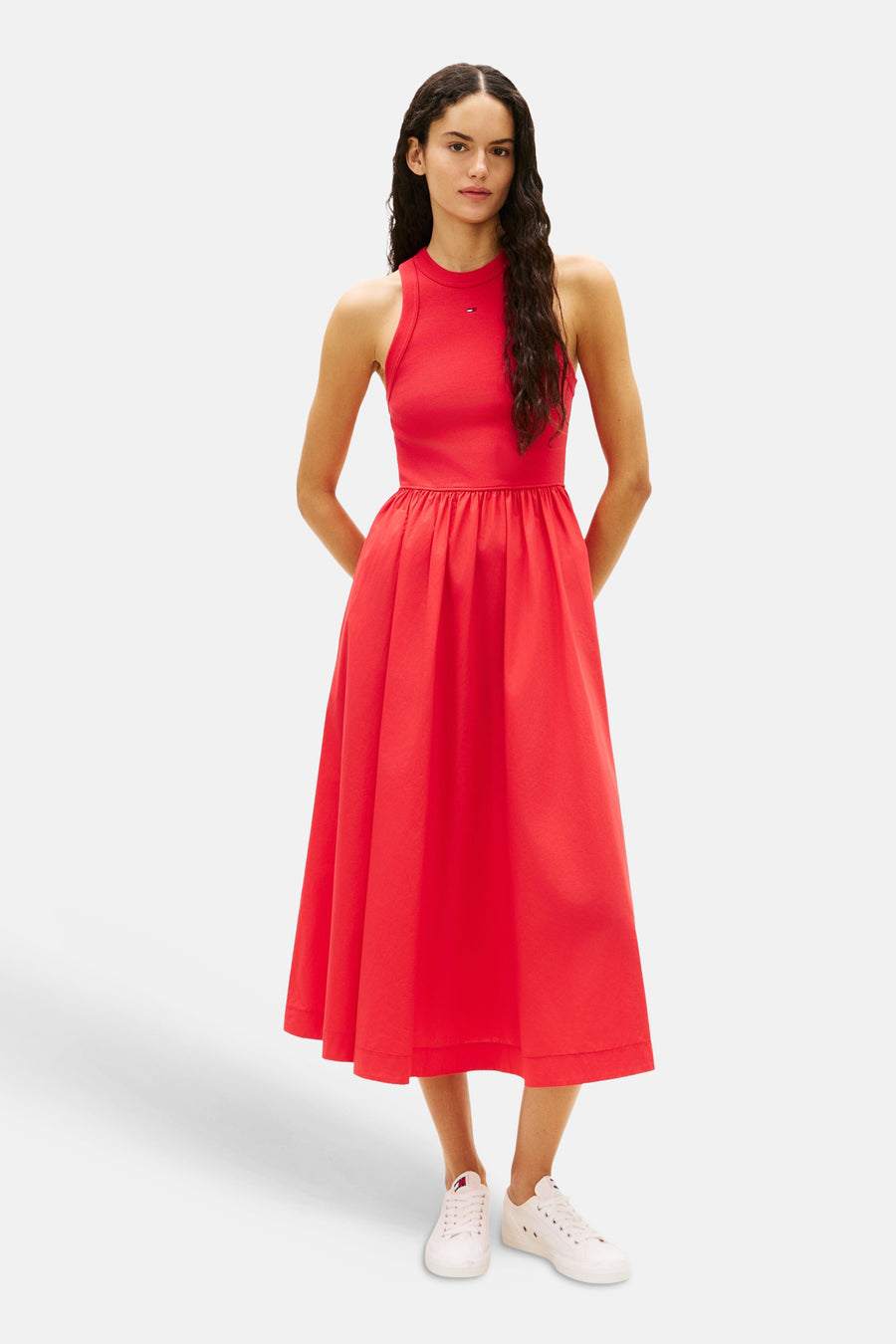 Robe rouge de TOMMY JEANS, coupe midi avec une jupe ample et des chaussures blanches.