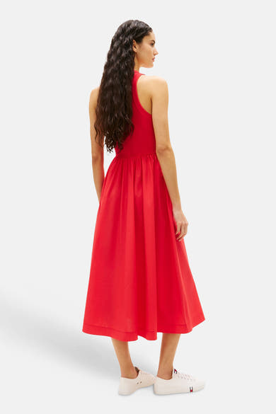 Robe rouge de TOMMY JEANS, avec une coupe évasée et longueur midi, portée avec des chaussures blanches.
