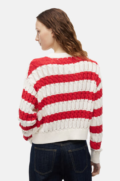 Wit-rood gestreepte trui met ronde hals van TOMMY JEANS in opengebreide stof, van achteren gezien, gedragen met een donkere spijkerbroek.