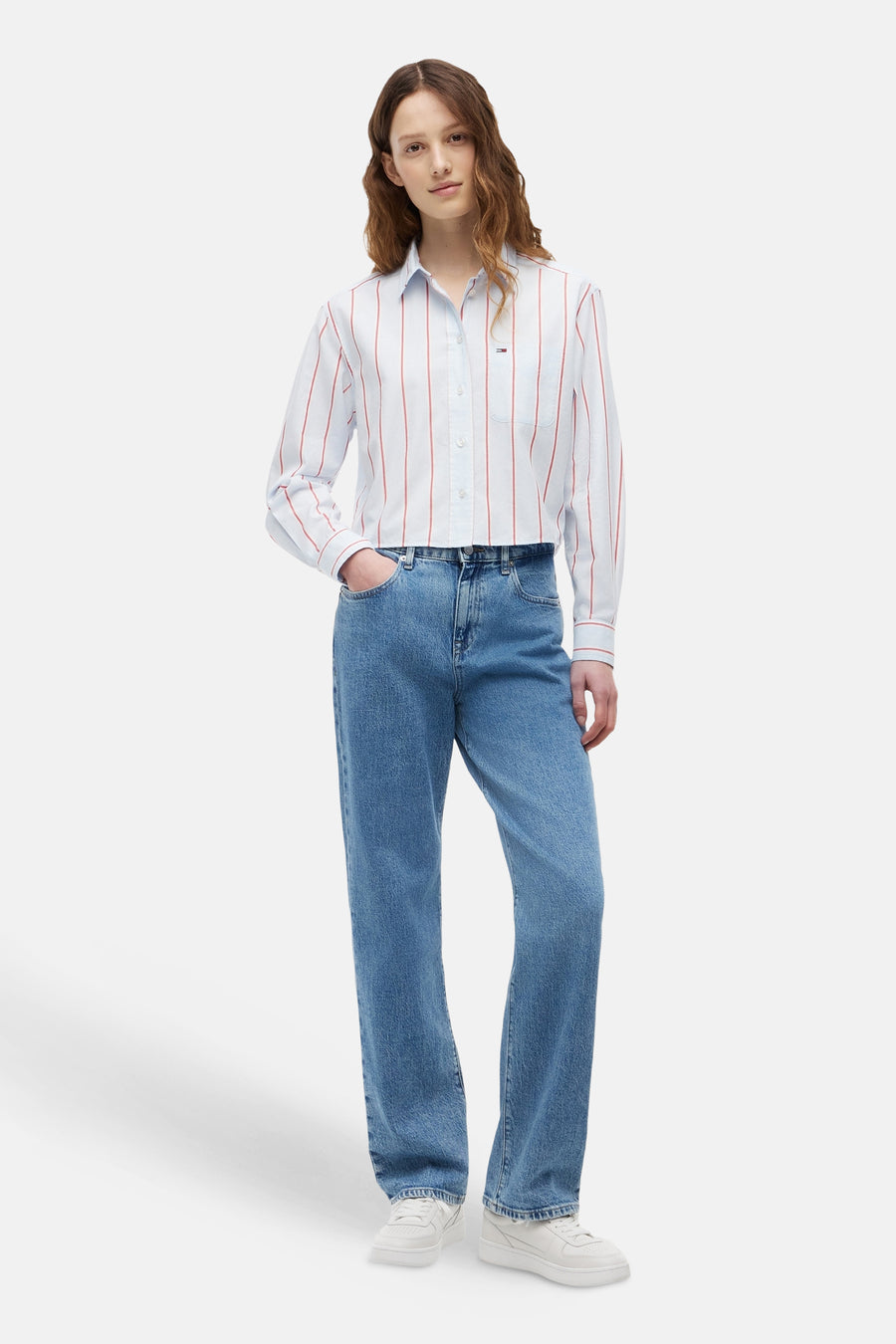 Wit overhemd met fijne rode strepen van TOMMY JEANS, kort model, gedragen met een blauwe jeans en witte sneakers.