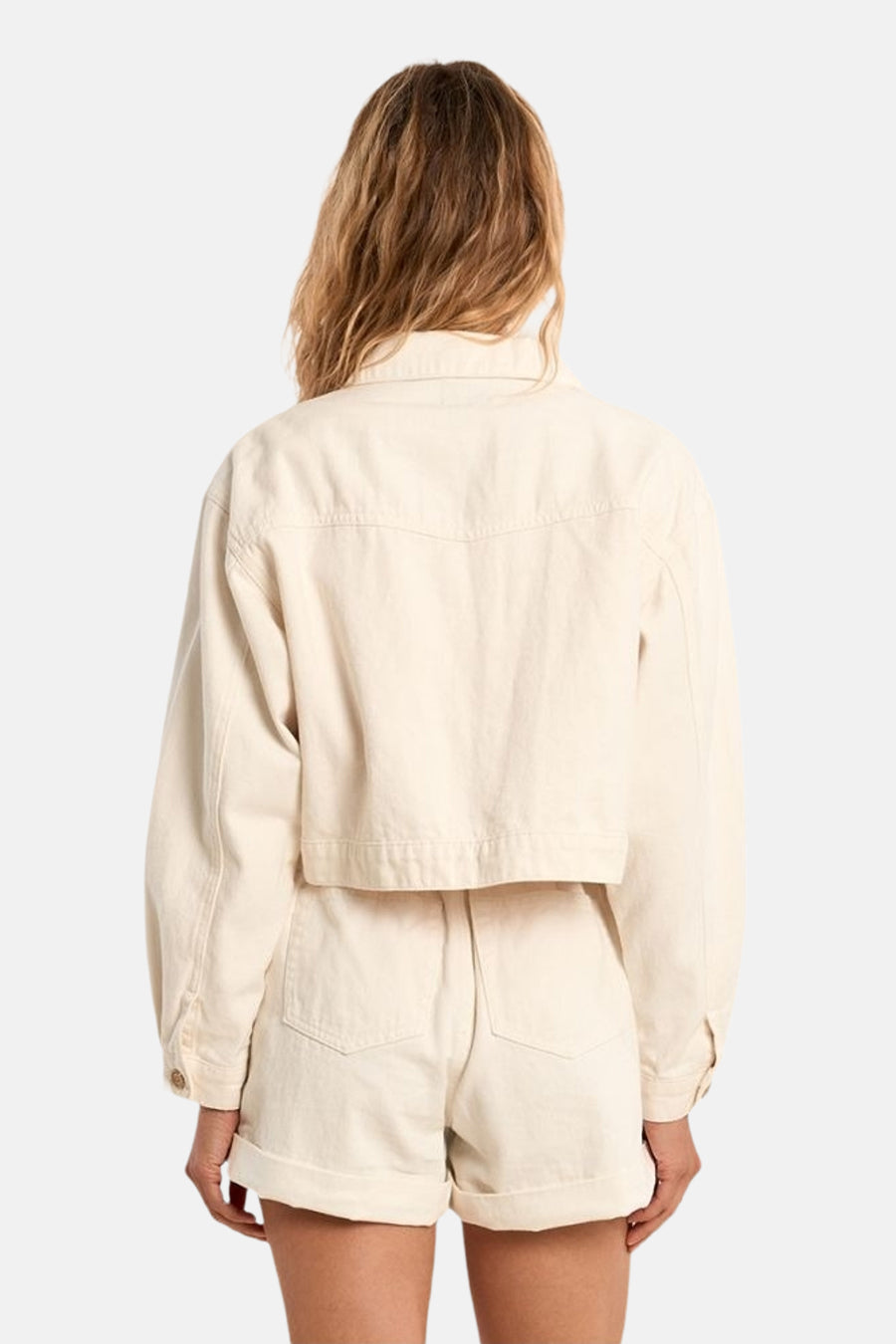 Veste en jean blanche de Molly Bracken, cropped et à manches longues, portée de dos avec un short assorti.