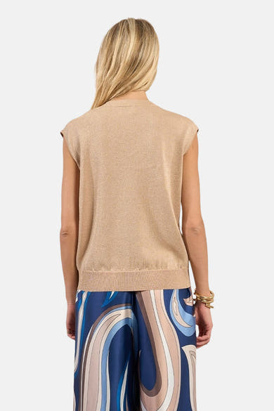 Top sans manches beige de Molly Bracken, avec un tissu légèrement brillant porté avec un pantalon à motif abstrait.
