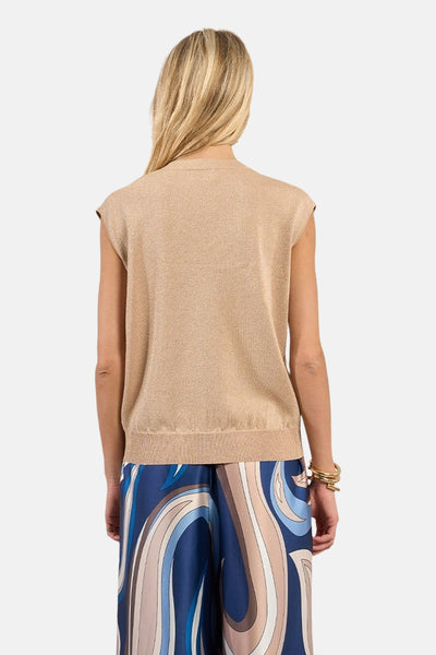 Top sans manches beige de Molly Bracken, avec un tissu légèrement brillant porté avec un pantalon à motif abstrait.
