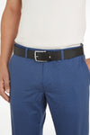 Ceinture noire par TOMMY JEANS avec boucle argentée, portée avec un pantalon texturé bleu et une chemise blanche.
