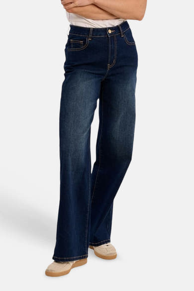 Wijde spijkerbroek in middinblauw denim van Molly Bracken, achterkant, hoge taille, met contrasterende stiksels, leren etiket en beige sneakers.