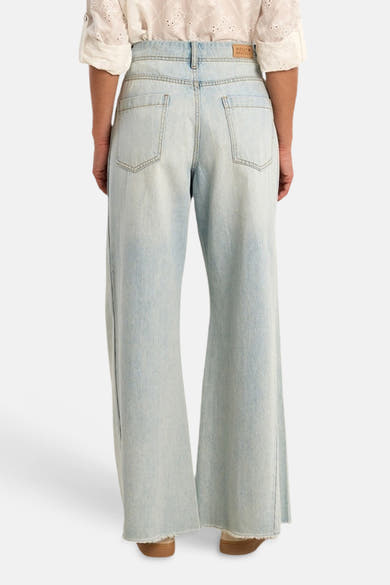 Jean large en denim bleu clair de Molly Bracken, vue de dos, avec étiquette sur la ceinture et ourlets effilochés.