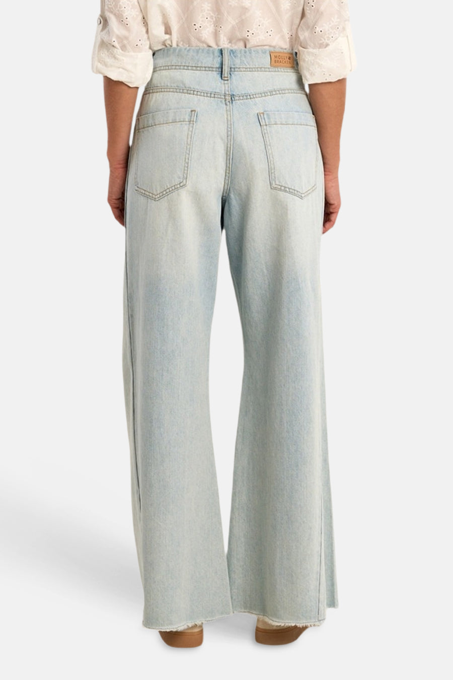 Jean large en denim bleu clair de Molly Bracken, vue de dos, avec étiquette sur la ceinture et ourlets effilochés.