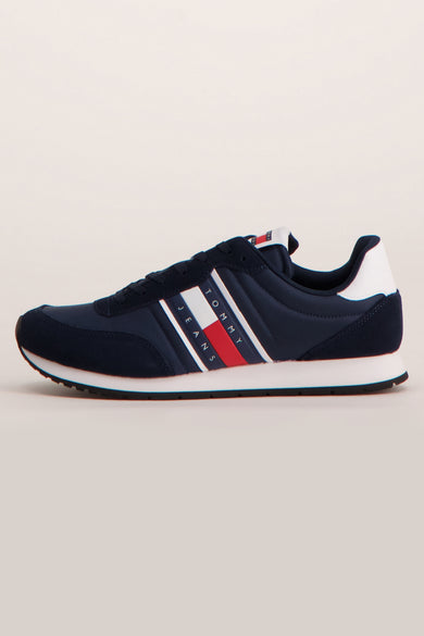 Baskets bleues de TOMMY JEANS avec des rayures rouges, blanches et bleu marine sur le côté.