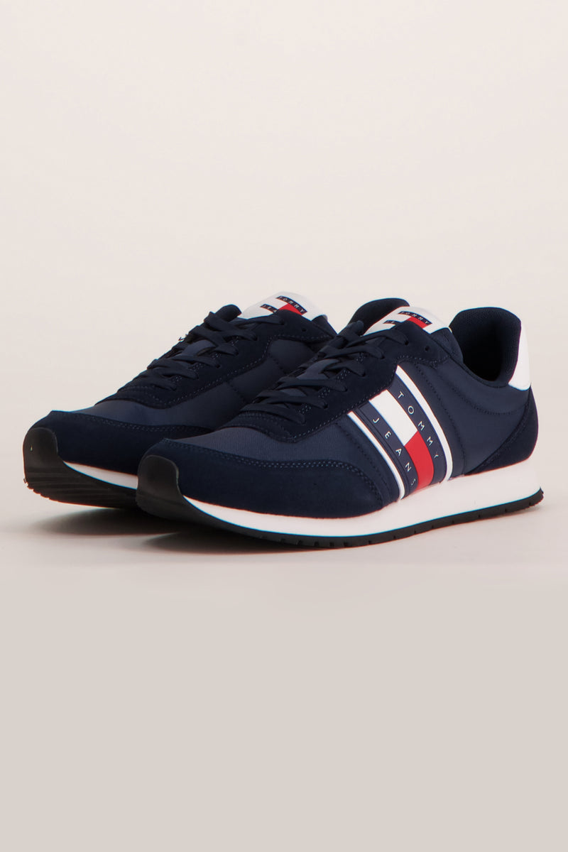 Baskets bleues de Tommy Jeans, avec rayures blanches et rouges sur le côté.